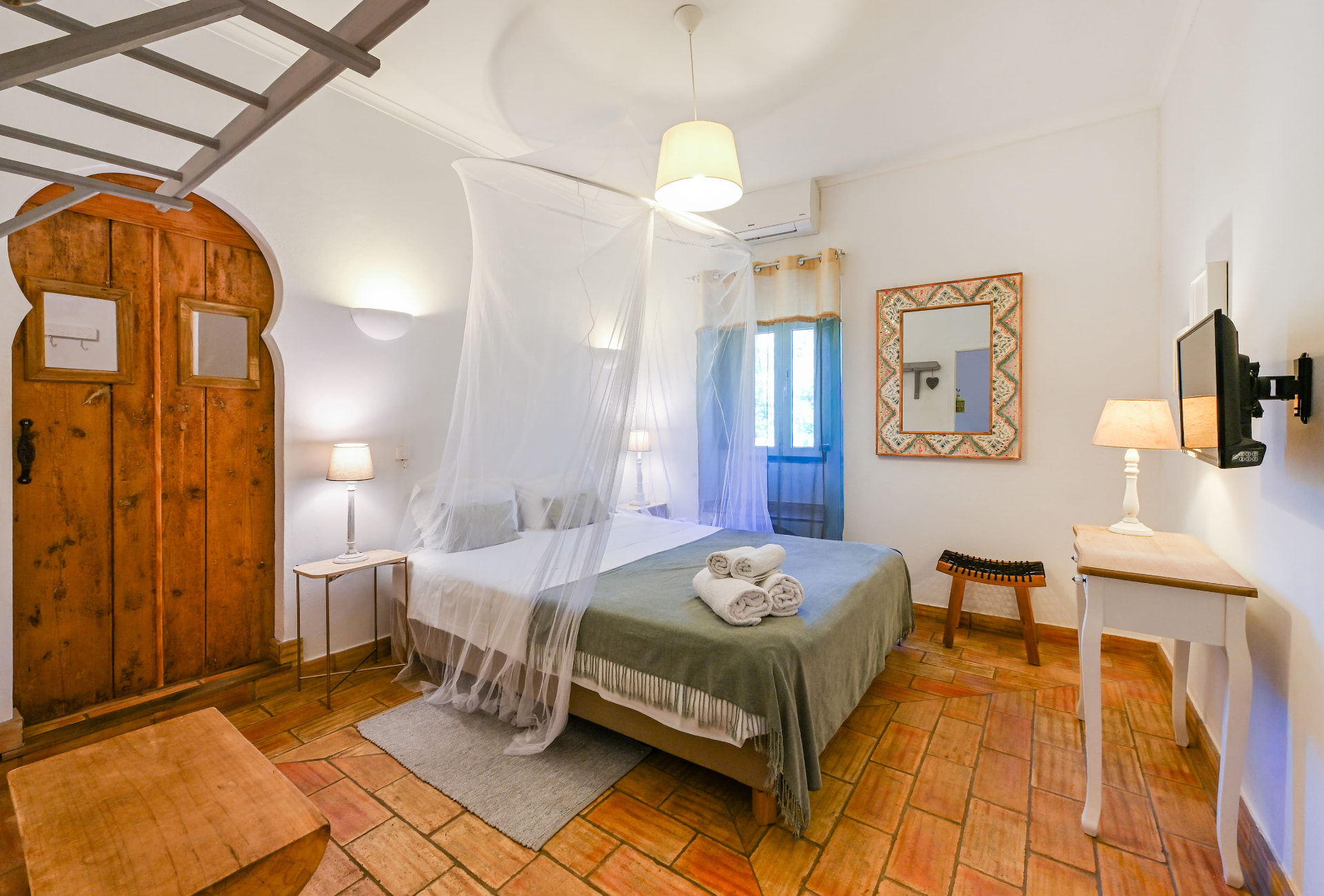 Quarto da Casa da Tia Amália com mosquiteiro branco e pavimento em tijoleira